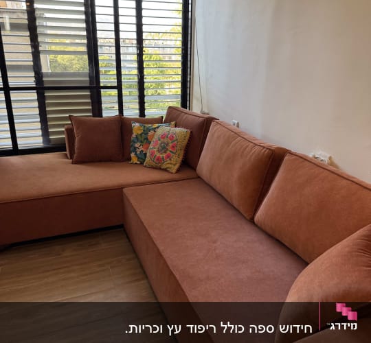 ספה חומה עם כריות צבעוניות על רצפת עץ